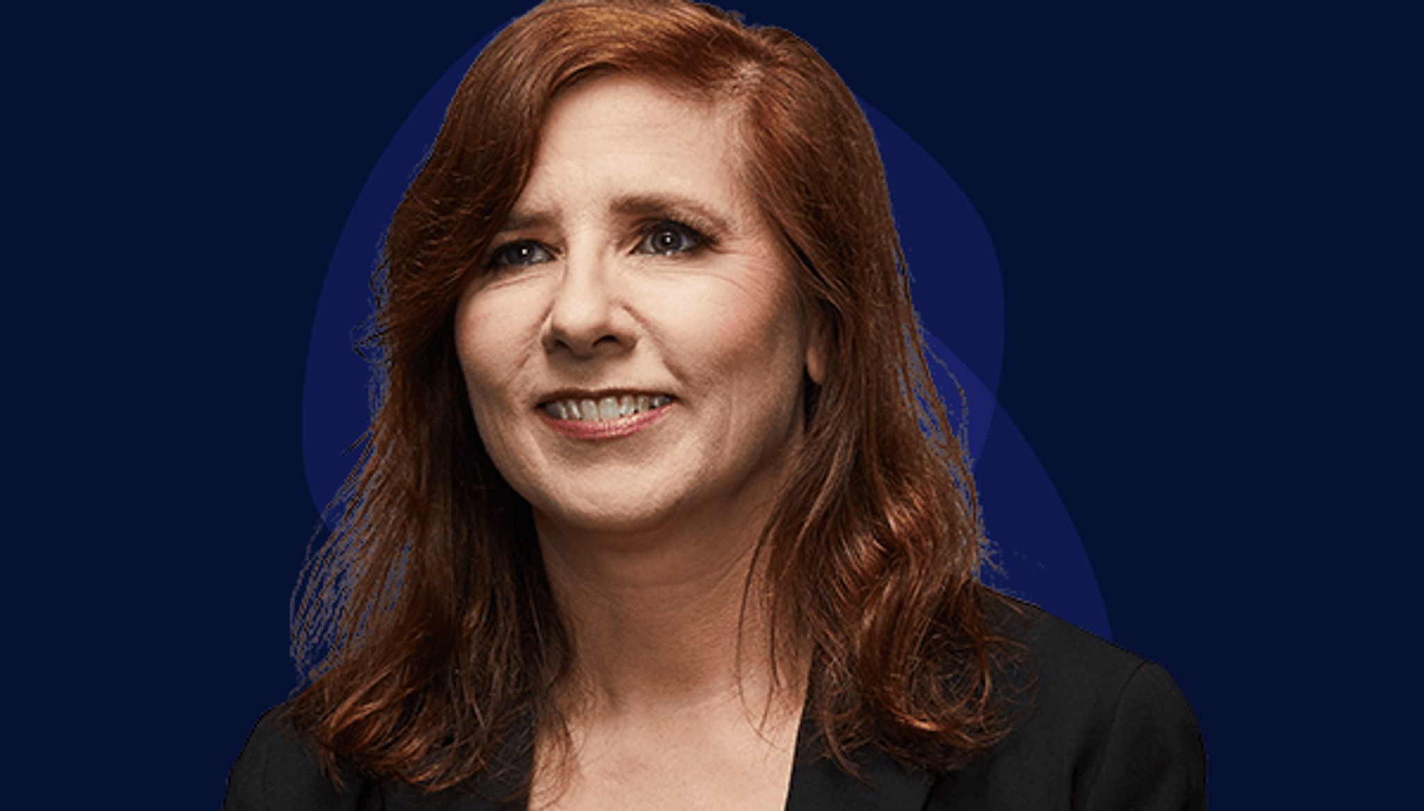 Annette's story White female in late forties with shoulder length, auburn hair wearing black V-neck blazer smiling to left of camera.